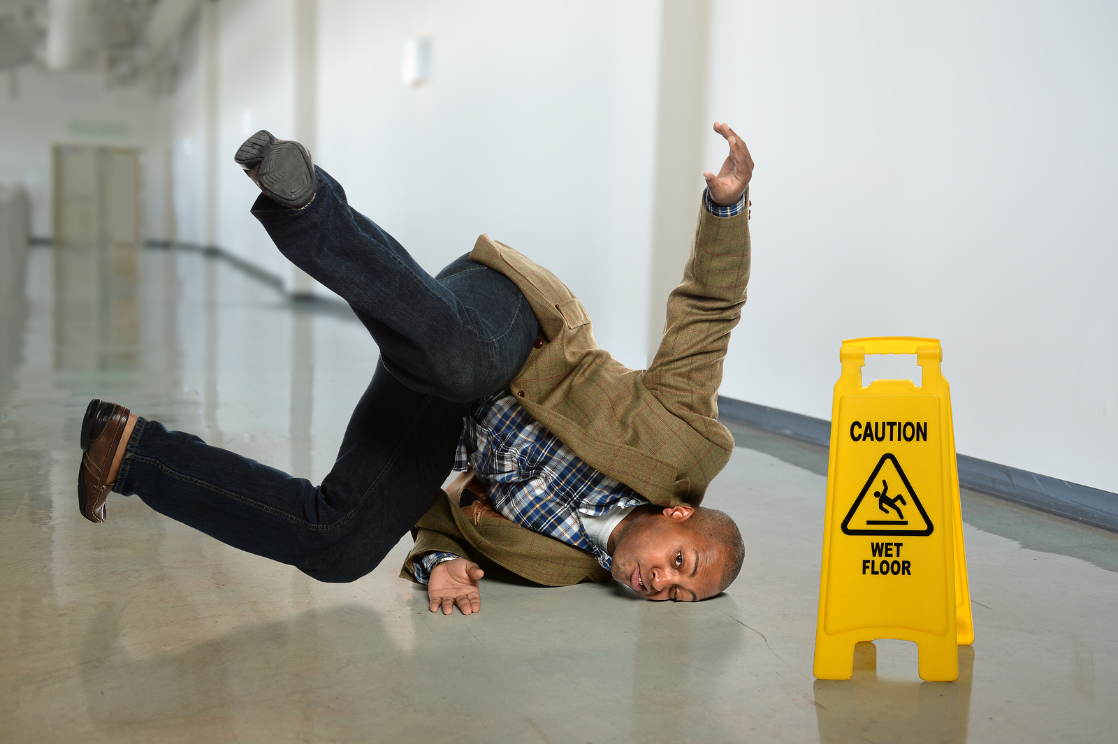 African American businessman falling on wet floor in office